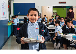 Equitas academy student holding lunch tray with healthy food in cafeteria in Los Angele